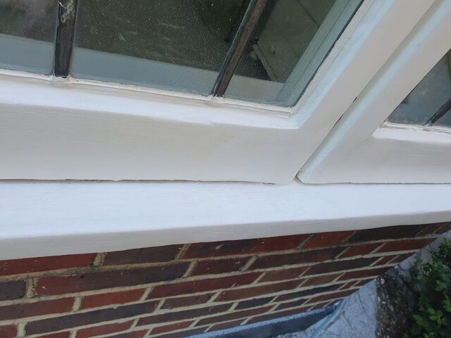 White painted bay window frame and sill above red brickwork