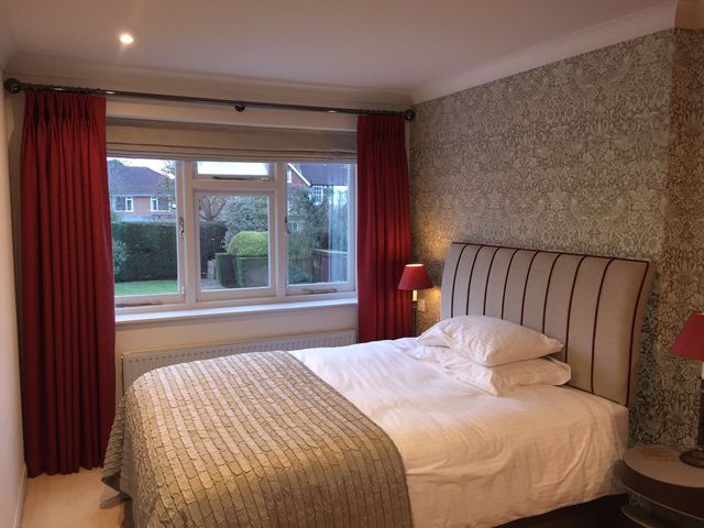 Bedroom with a damask-papered wall and an upholstered headboard with stripes