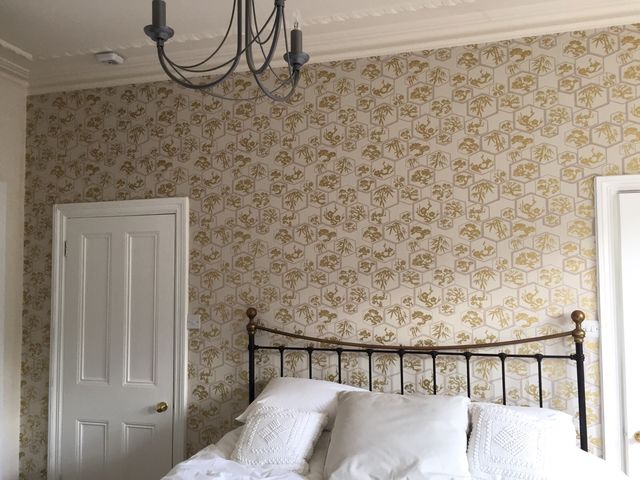 Bedroom with floral wallpaper and a metal bed frame