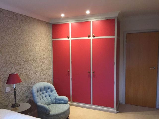 Bedroom with grey patterned wallpaper and a wardrobe whose doors are painted red