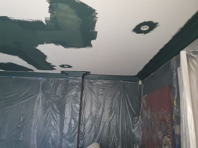 Ceiling part painted dark green with green cornice above walls masked in plastic sheeting