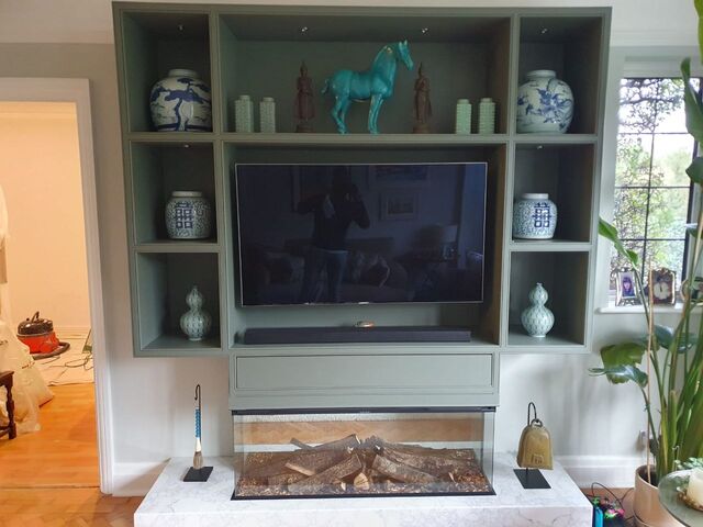 Media wall shelving and alcoves painted around a television above a fireplace