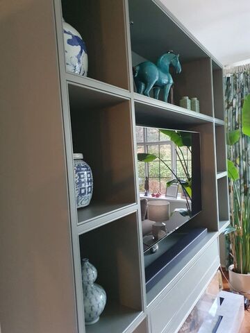 Painted media wall shelving unit with a television and ornaments in a living room