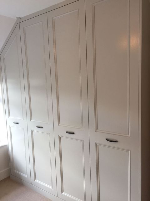 Tall panelled wardrobe doors painted off-white beneath a sloped ceiling