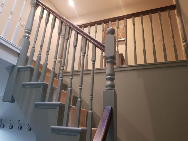Grey painted staircase balustrade and spindles seen from below, with a dark handrail