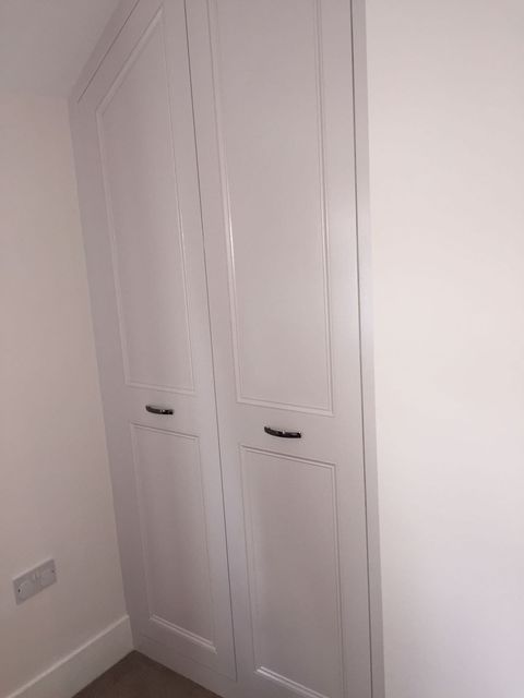 Tall white fitted wardrobe with panelled doors