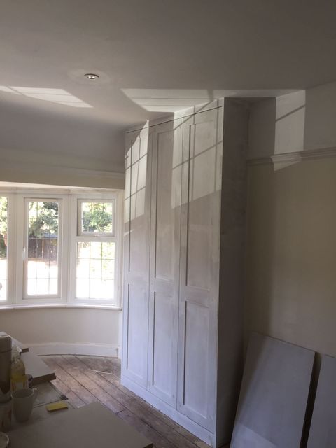 Tall off-white wardrobe doors beside a white painted curved bay window
