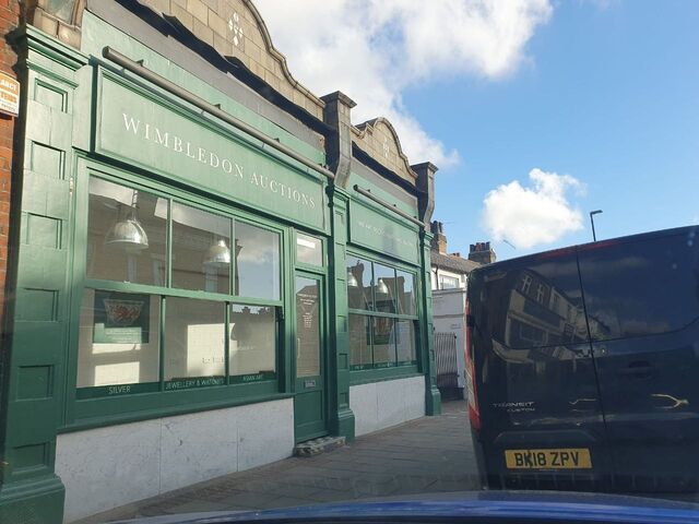 Completed green painted shopfront with a white plinth seen at an angle