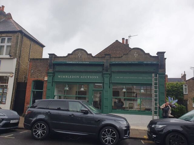 Green painted auction house shopfront with white lettering, seen from the street