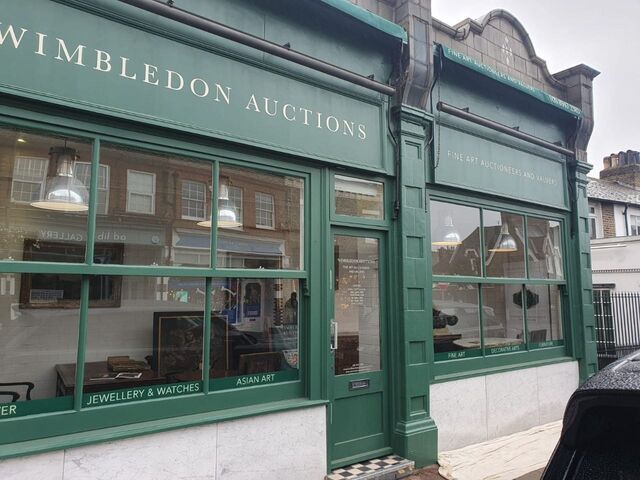 Close-up of a green painted shopfront with white lettering and window frames